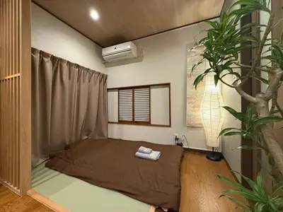 a bedroom with a bed in a room with a tree at nestay villa tokyo ueno in Tokyo