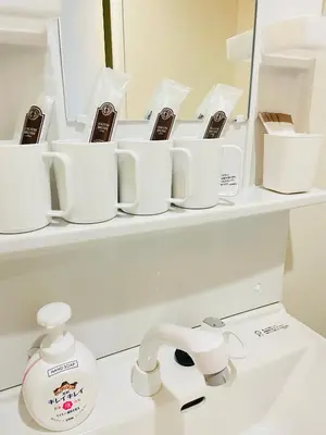 a bathroom sink with white cups and a mirror at T-Hotel \u6d45\u8349 in Tokyo