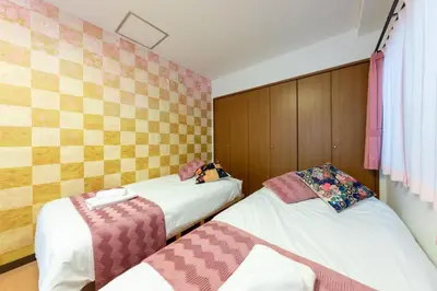 a bedroom with two beds and a wall at Joint Court Kameido in Tokyo
