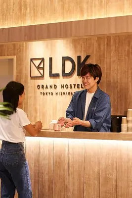 a man and a woman standing at a counter at GRAND HOSTEL LDK Tokyo Nishikasai -GRAND OPENING In May 2025- in Tokyo
