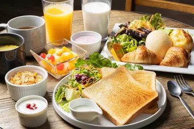 a table with two plates of breakfast foods and juice at GRAND HOSTEL LDK Tokyo Nishikasai -GRAND OPENING In May 2025- in Tokyo
