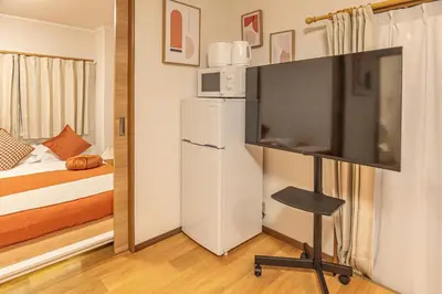 a living room with a tv and a bed and a bedroom at Shinjuku 2 stops new mansion free WiFi nakano area in Tokyo