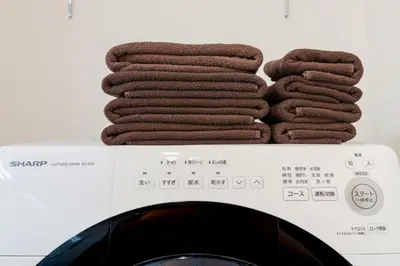 a pile of towels sitting on top of a washing machine at Househotel EKODA 201 HE21 in Tokyo
