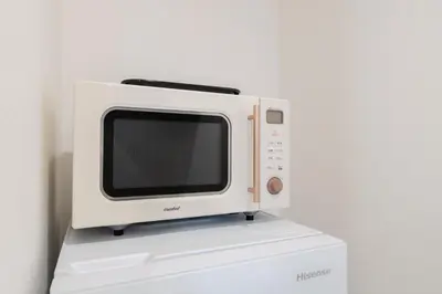 a microwave sitting on top of a white refrigerator at Househotel EKODA 201 HE21 in Tokyo