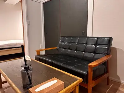a black leather couch in a room with a table at LoveAsakusaBigSpaceModernHome 浅草寺6分 浅草寺駅10分 2-8人 成田&羽田空港直通 in Tokyo