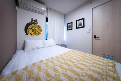 a bedroom with a bed with a cat picture on the wall at \u65b0\u5bbf\u539f\u753a\u8cb8\u5207\u4e00\u8ed2\u5bb6 in Tokyo