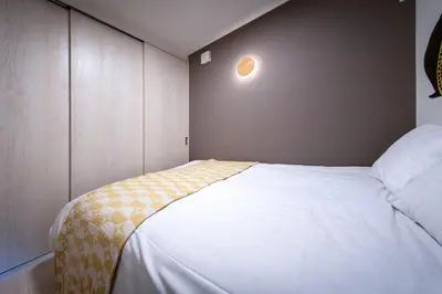 a bedroom with a white bed with a yellow blanket on it at \u65b0\u5bbf\u539f\u753a\u8cb8\u5207\u4e00\u8ed2\u5bb6 in Tokyo