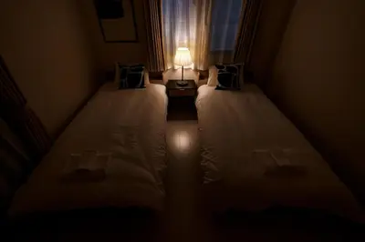 a small room with two beds with a lamp on it at Yahiro Villa in Tokyo