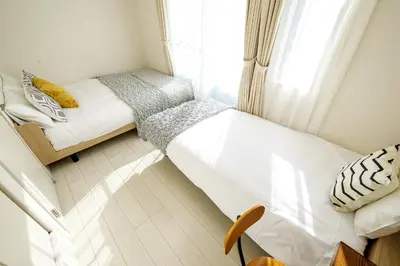 a small bedroom with two beds and a window at Yahiro Villa in Tokyo