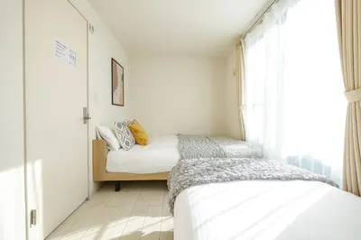 two beds in a small bedroom with a window at Yahiro Villa in Tokyo