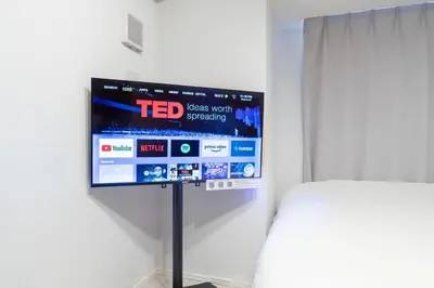 a tv on a wall in a room with a bed at \u30b8\u30a7\u30ce\u30f4\u30a3\u30a2\u68ee\u4e0b\u30b9\u30ab\u30a4\u30ac\u30fc\u30c7\u30f3 in Tokyo