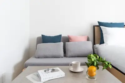 a living room with a couch with pillows and a table at \u30b8\u30a7\u30ce\u30f4\u30a3\u30a2\u68ee\u4e0b\u30b9\u30ab\u30a4\u30ac\u30fc\u30c7\u30f3 in Tokyo