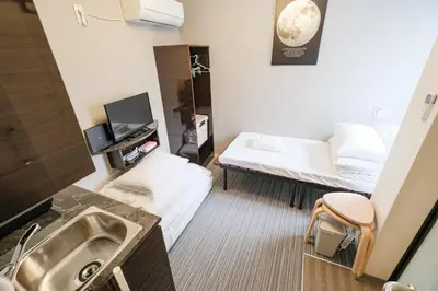 a small room with two beds and a sink at Mi-HOTEL QUALIA SHINJUKU in Tokyo