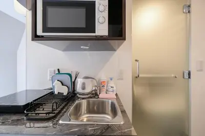 a kitchen with a sink and a microwave at Mi-HOTEL QUALIA SHINJUKU in Tokyo
