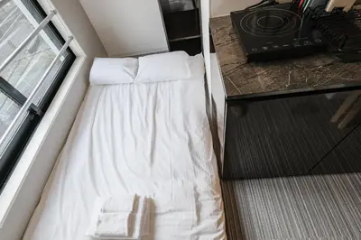 a bed in a small room with a window at Mi-HOTEL QUALIA SHINJUKU in Tokyo
