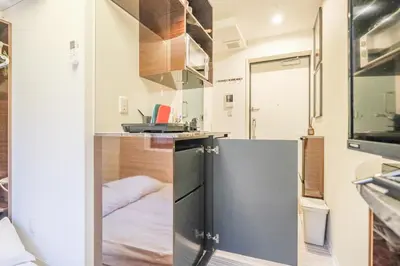 a small kitchen with a refrigerator and a sink at Mi-HOTEL QUALIA SHINJUKU in Tokyo
