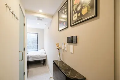 a hallway with a table and a bed in a room at Mi-HOTEL HEARTS SHINJUKU in Tokyo