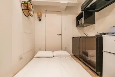 a small white kitchen with a bed in the corner at Mi-HOTEL HEARTS SHINJUKU in Tokyo