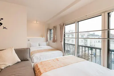 two beds in a room with a large window at saiei hotel 401 in Tokyo