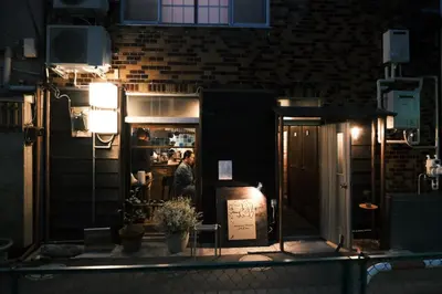a man standing inside of a restaurant at night at Hotel Suzumeya Tsukiji plus kitchen in Tokyo