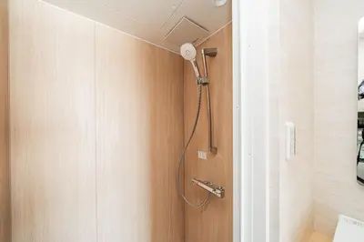 a shower in a bathroom with a wooden door at saiei hotel 501 in Tokyo