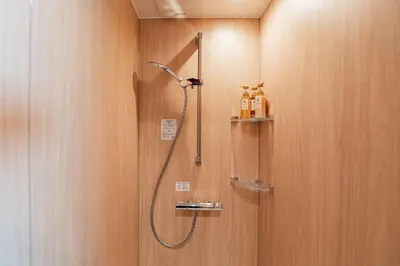 a shower in a bathroom with wooden walls at saiei hotel 502 in Tokyo