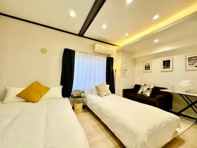 a bedroom with two beds and a couch in it at Yochomachi Hostel\u82e5\u677eSJ0357 in Tokyo