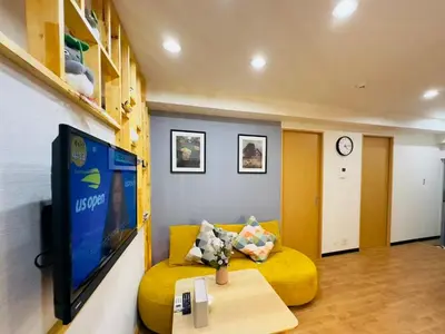 a living room with a yellow couch and a tv at Yochomachi Hostel\u82e5\u677eSJ0357 in Tokyo