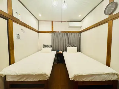 two beds in a room with a clock on the wall at Oji House-KI0022 in Tokyo