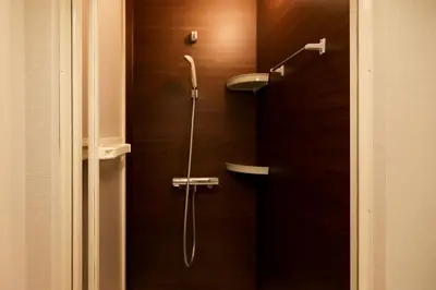 a shower in a bathroom with a wooden door at 5 minutes on foot from tokyo Asakusa Station!A beautiful house that has been fully renovated in 2024 for one group per day\u6771\u4eac\u96f7\u9580\u304b\u3089\u5f92\u6b694\u52061\u65e51\u7d44\u9650\u5b9a\u8cb8\u52072024\u5e74\u5168\u9762\u30ea\u30d5\u30a9\u30fc\u30e0\u6e08\u307f\u306e\u7dba\u9e97\u306a\u4e00\u8ed2\u5bb6 in Tokyo