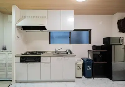 a kitchen with white cabinets and a sink and a refrigerator at Kasai Light Luxury House 101 in Tokyo