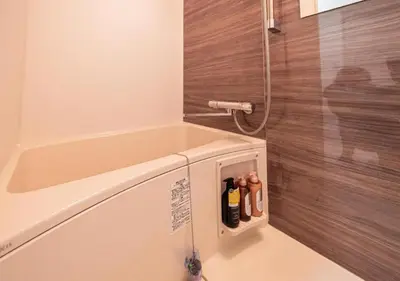 a bathroom with a shower with a tub and bottles at Kasai Light Luxury Hotel 201 in Tokyo