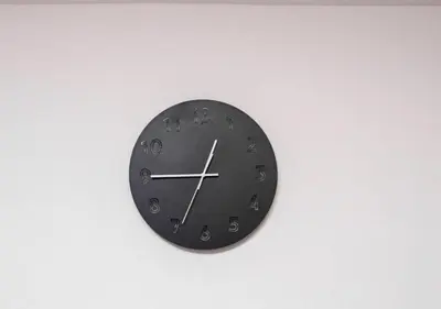a black clock hanging on a white wall at Kasai Light Luxury Hotel 201 in Tokyo