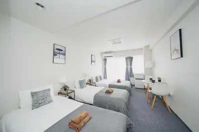 a hotel room with three beds and a desk at 4 minutes walk from Shibuya Station 3 beds in Tokyo