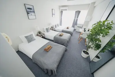 two beds in a room with potted plants at 4 minutes walk from Shibuya Station 3 beds in Tokyo
