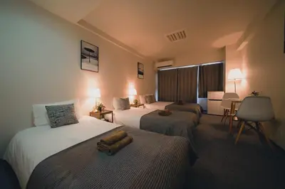 a hotel room with two beds and a desk at 4 minutes walk from Shibuya Station 3 beds in Tokyo