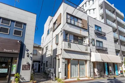 a tall white building on the side of a street at \u3077\u3075\u304b\u30bf\u30de\u30ce\u30a4-Pufuka Tamanoi in Tokyo