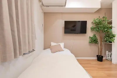 a bedroom with a bed and a tv on a wall at Urban Villa Sumida in Tokyo