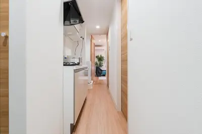 a hallway leading into a kitchen with white walls and wood floors at Urban Villa Sumida in Tokyo