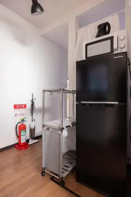 a black refrigerator with a microwave on top of it at Omori House in Tokyo