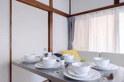 a dining room table with white cups and saucers at Omori House in Tokyo