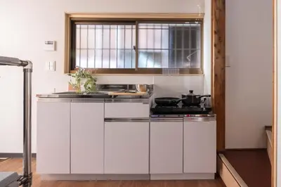a white kitchen with a stove and a window at Omori House in Tokyo