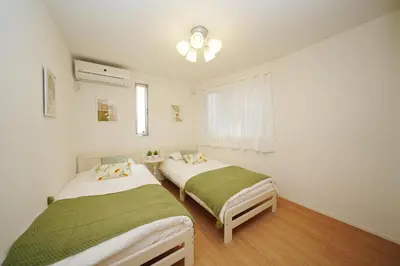 two beds in a room with white walls and wood floors at Near Skytree 90sqm 4BDR! 4mins to station! in Tokyo
