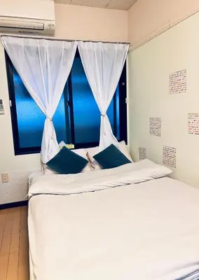 a white bed with blue pillows and a window at The Yumi Shinjuku in Tokyo