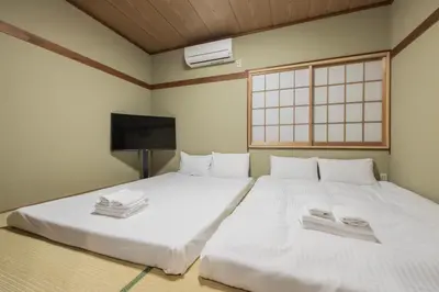 two white beds in a room with a flat screen tv at self-check in-shinjuku-windhouse in Tokyo
