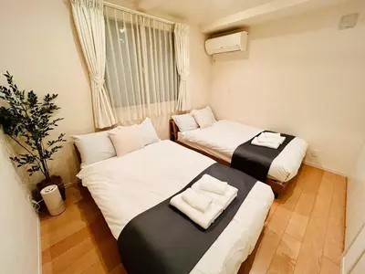 two beds in a small room with a window at \u6e0b\u8c375\u5206 \u65b0\u5bbf15\u5206 \u4e09\u8ed2\u8336\u5c4b\u99c5\u5f92\u6b694\u5206 8\u540d\u5bbf\u6cca\u53ef \u4e00\u68df\u8cb8\u5207 24\u6642\u9593\u30b9\u30fc\u30d1\u30fc\u5f92\u6b693\u5206 in Tokyo