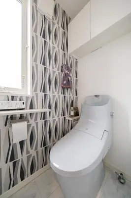 a white toilet in a bathroom with a patterned wall at QiQi House Elegance in Sumida Yahiro Skytree Views & High-End Comfort for 6 people in Tokyo