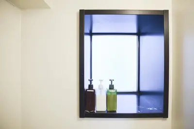 a bathroom mirror with two bottles on a table at self-check in-\u30ef\u30b3\u30fc\u30c9\u76ee\u767d in Tokyo