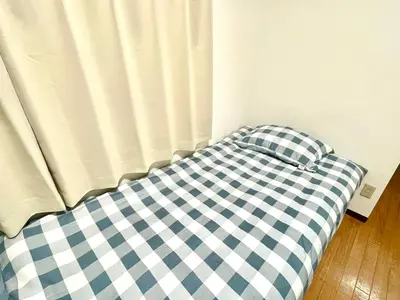 a bed with a blue and white checkered sheet at Tokyo West Shinjuku Entire House in Nishishinjuku-gochome in Tokyo