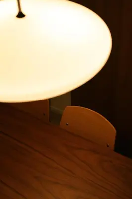 a table with a white lamp and a wooden chair at Urban House Koenji in Tokyo
